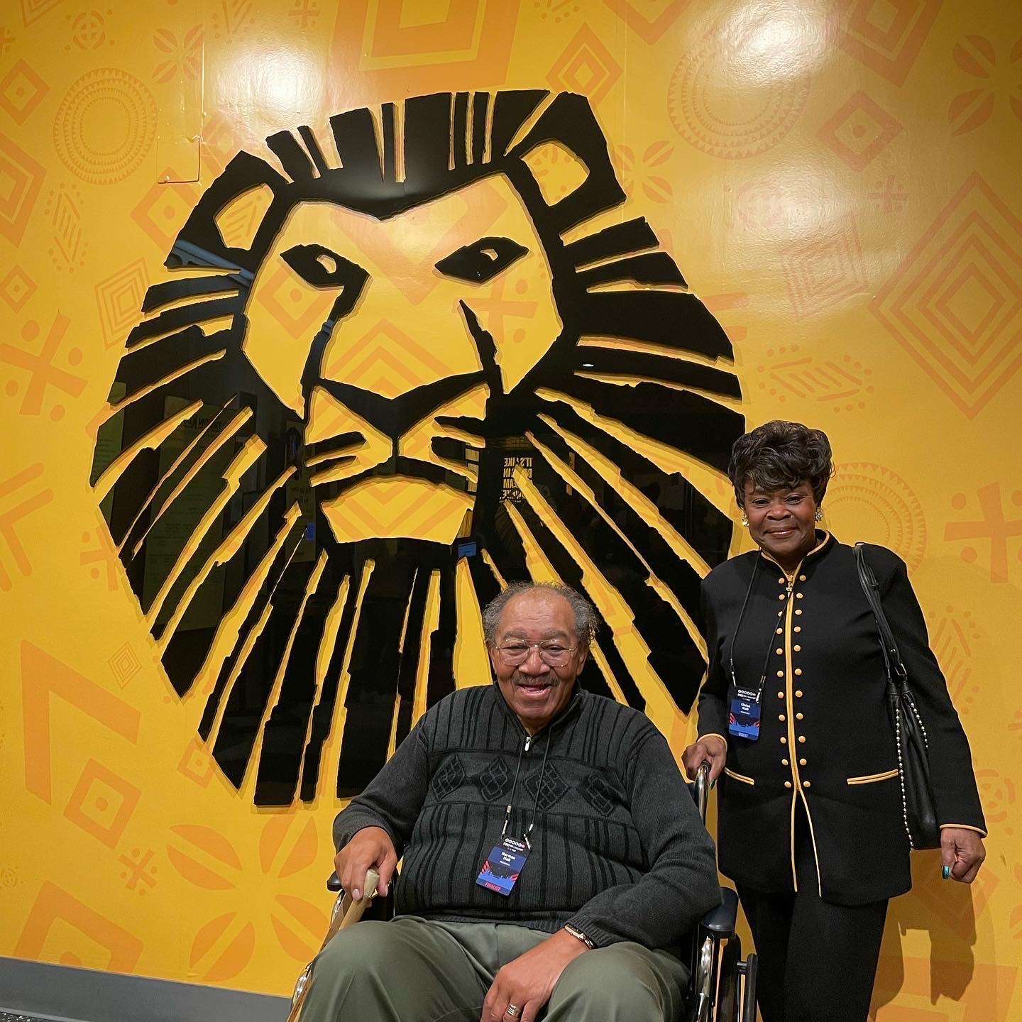 Norman and Eloise Hall in front of "The Lion King" sign.